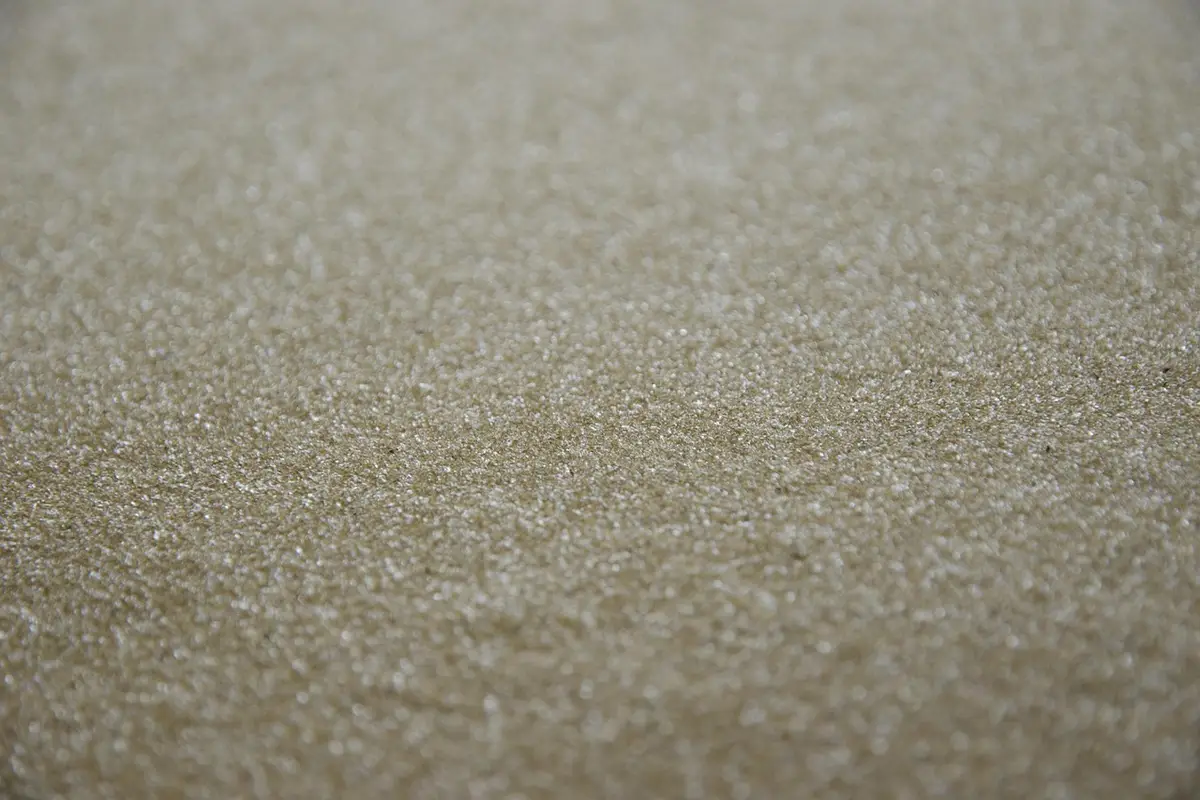 Macro close-up of a textured, granular abrasive surface with tiny shimmering particles