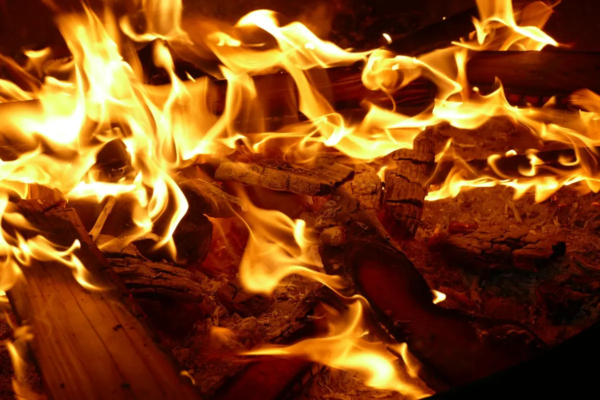 Close-up of vivid flames consuming ash logs in a wood-burning fire.