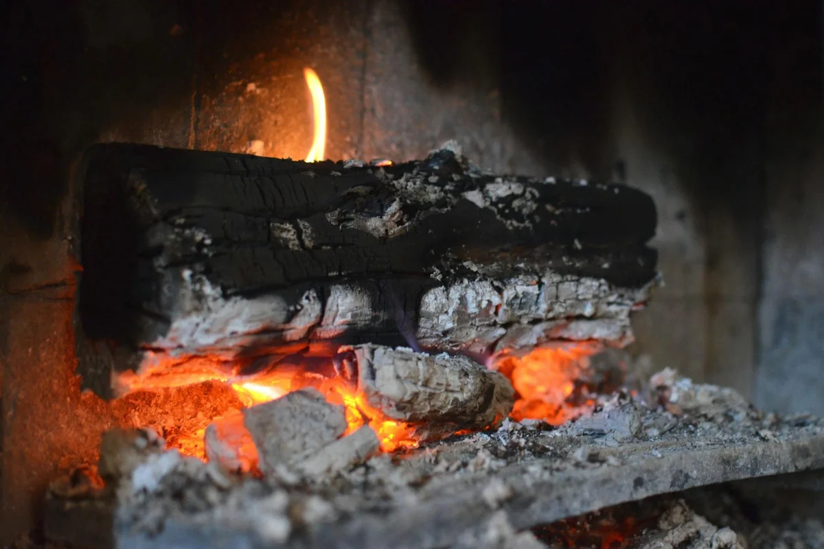 Close-up of glowing ash wood logs burning in a fireplace