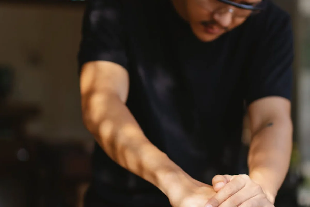 Close-up of a craftsman in a black shirt with hands clasped, symbolizing preparation for applying finish to outdoor lumber.