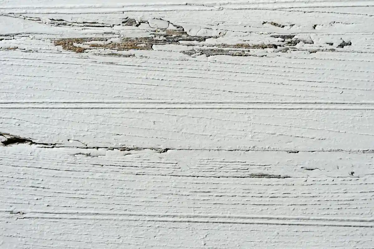 Close-up of distressed white-painted wood with chipped and peeling finish and visible grain
