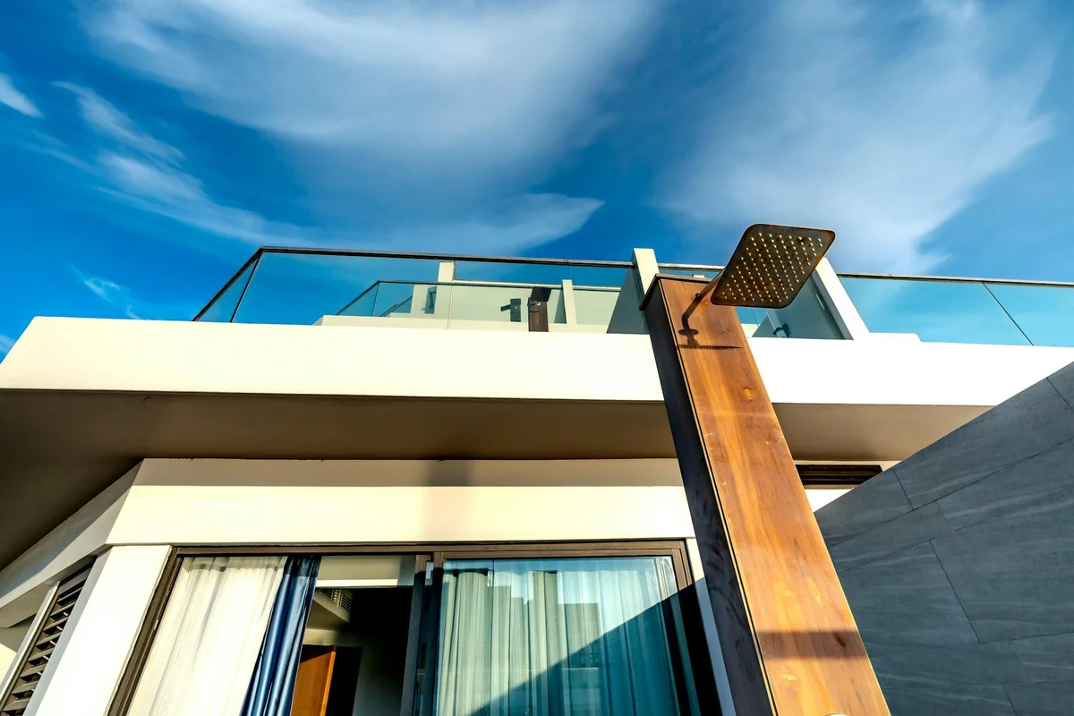 Modern building exterior with a rust-colored vertical beam and large glass doors against a blue sky.