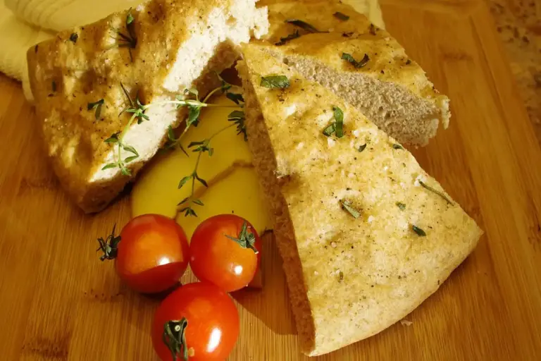 Slices of bread and fresh cherry tomatoes on a wooden cutting board with sprigs of thyme