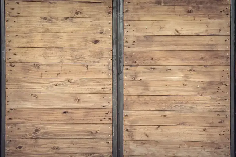 Close-up of weathered wooden planks with visible grain and knots, flanked by vertical metal trim.