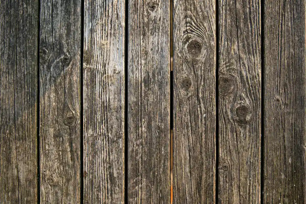 Close-up of weathered wooden planks with visible grain and knots, typical of coastal or high-humidity environments.