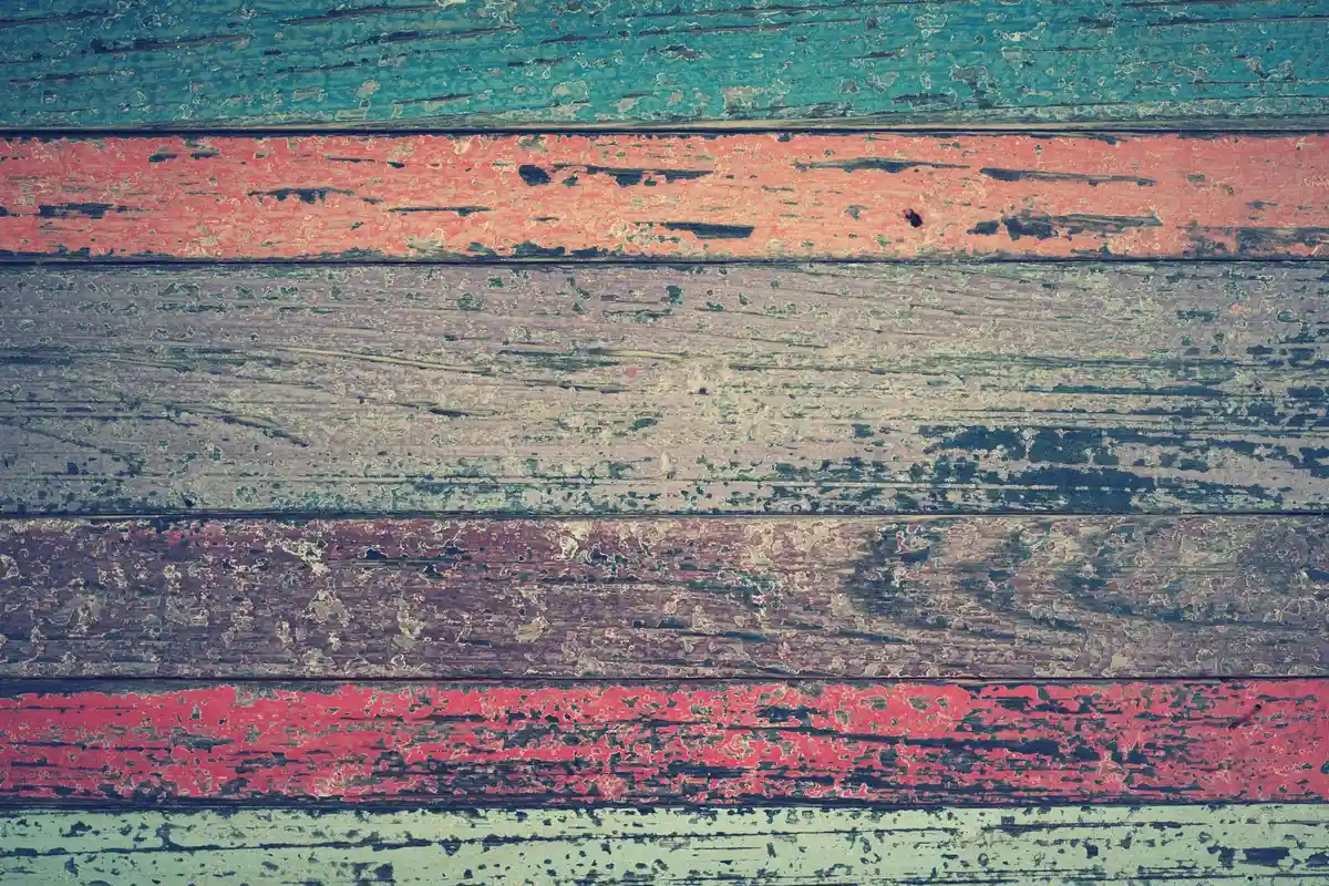 Colorful weathered wooden planks with chipped paint showing wood weathering and movement.