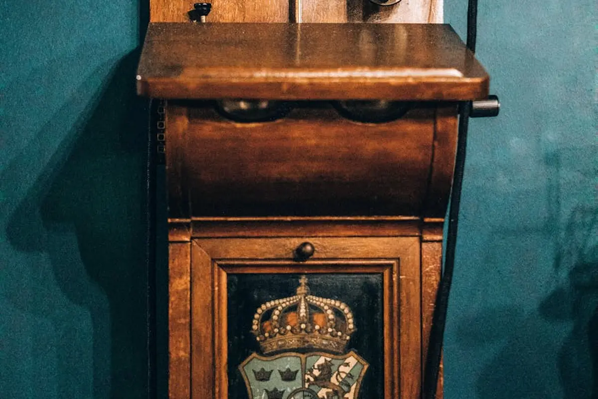 Vintage wooden cabinet with a crest emblem on a teal wall