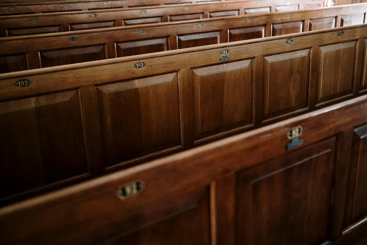 Rows of dark wood paneling with small metal fasteners, typical of cabinet or pew construction.