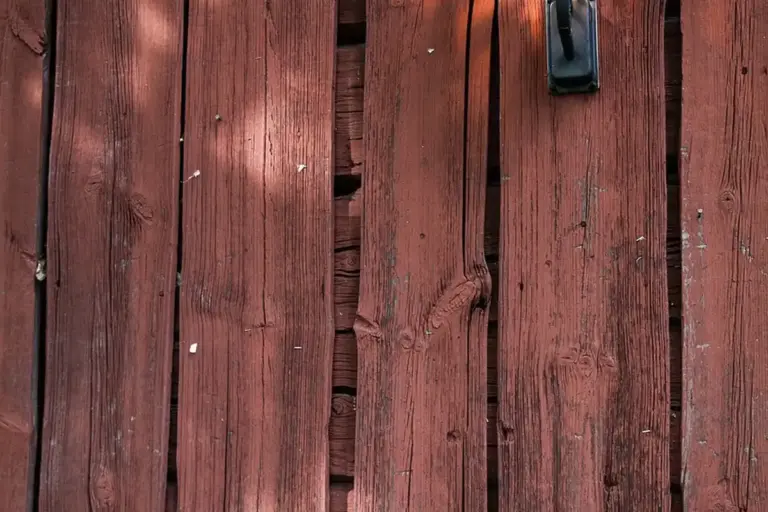 Close-up of red-stained wooden deck boards with visible grain and small dents.