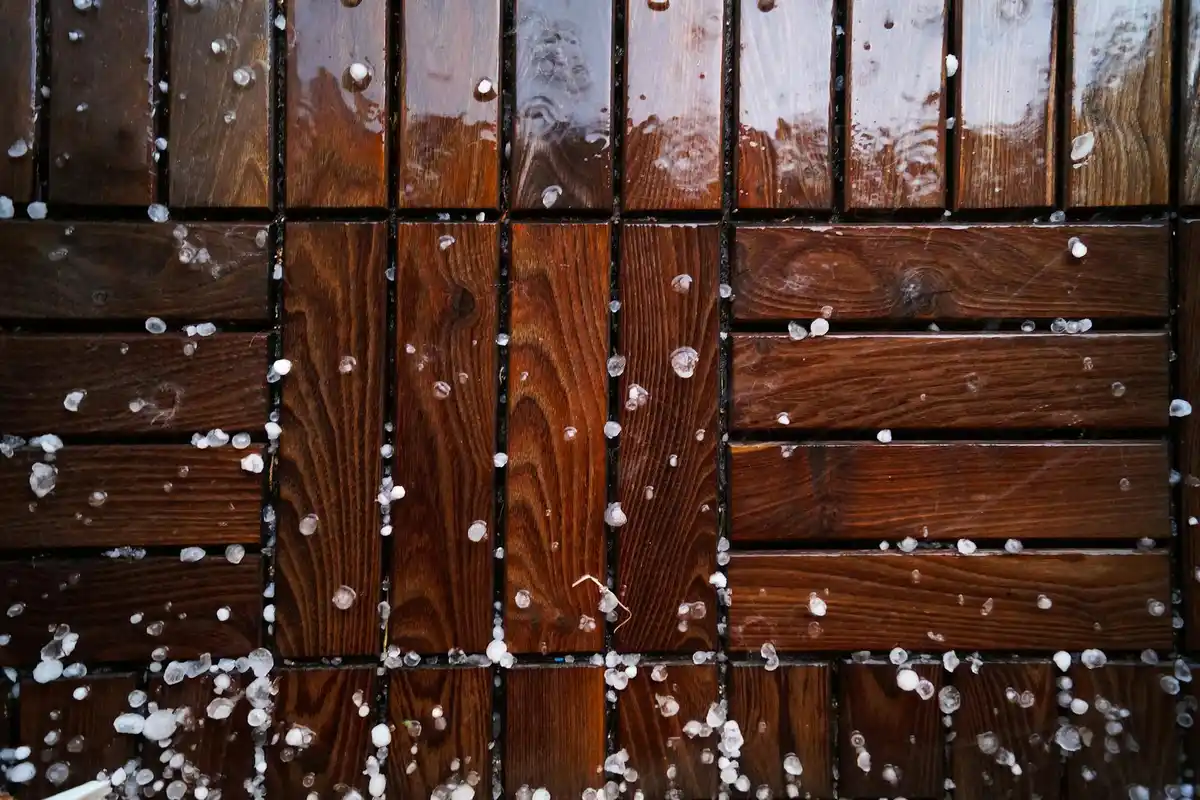 Close-up of dark wooden boards with small white droplets scattered across the surface, suggesting moisture exposure.