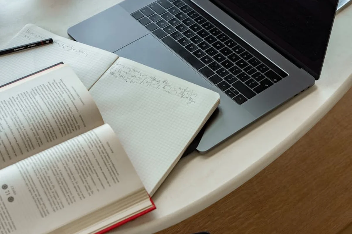 Laptop and notebooks on a desk, representing a workspace for discussing epoxy pot life, cure time, and heat management.