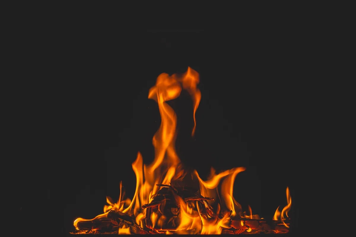 Bright orange flames and embers against a dark background, symbolizing heat-driven curing.