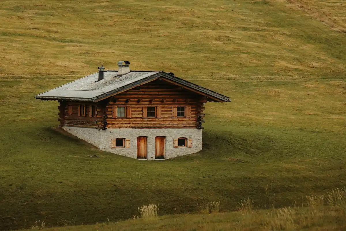 A wooden cabin on a grassy hillside.