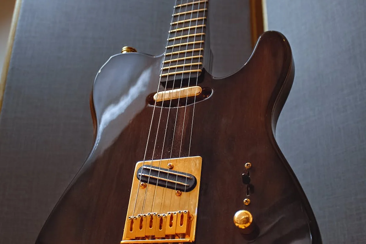 Close-up of a dark wood-finished electric guitar body with strings and gold hardware