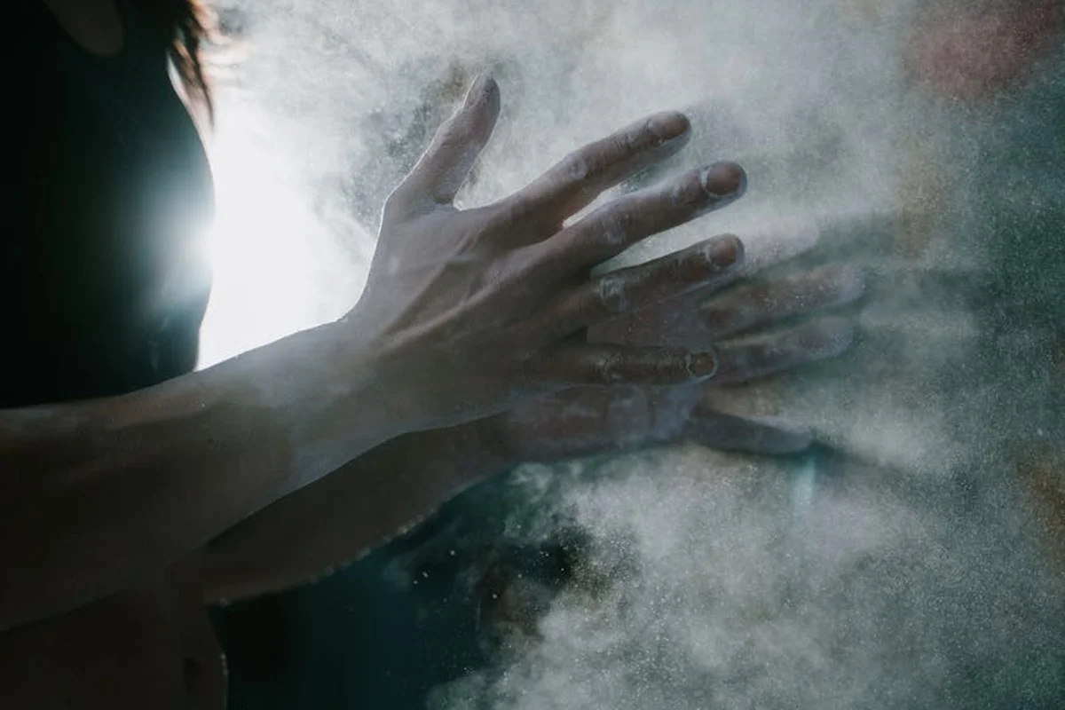 Close-up of hands moving through a cloud of dust or fumes, illustrating airflow and containment concepts in a workshop.