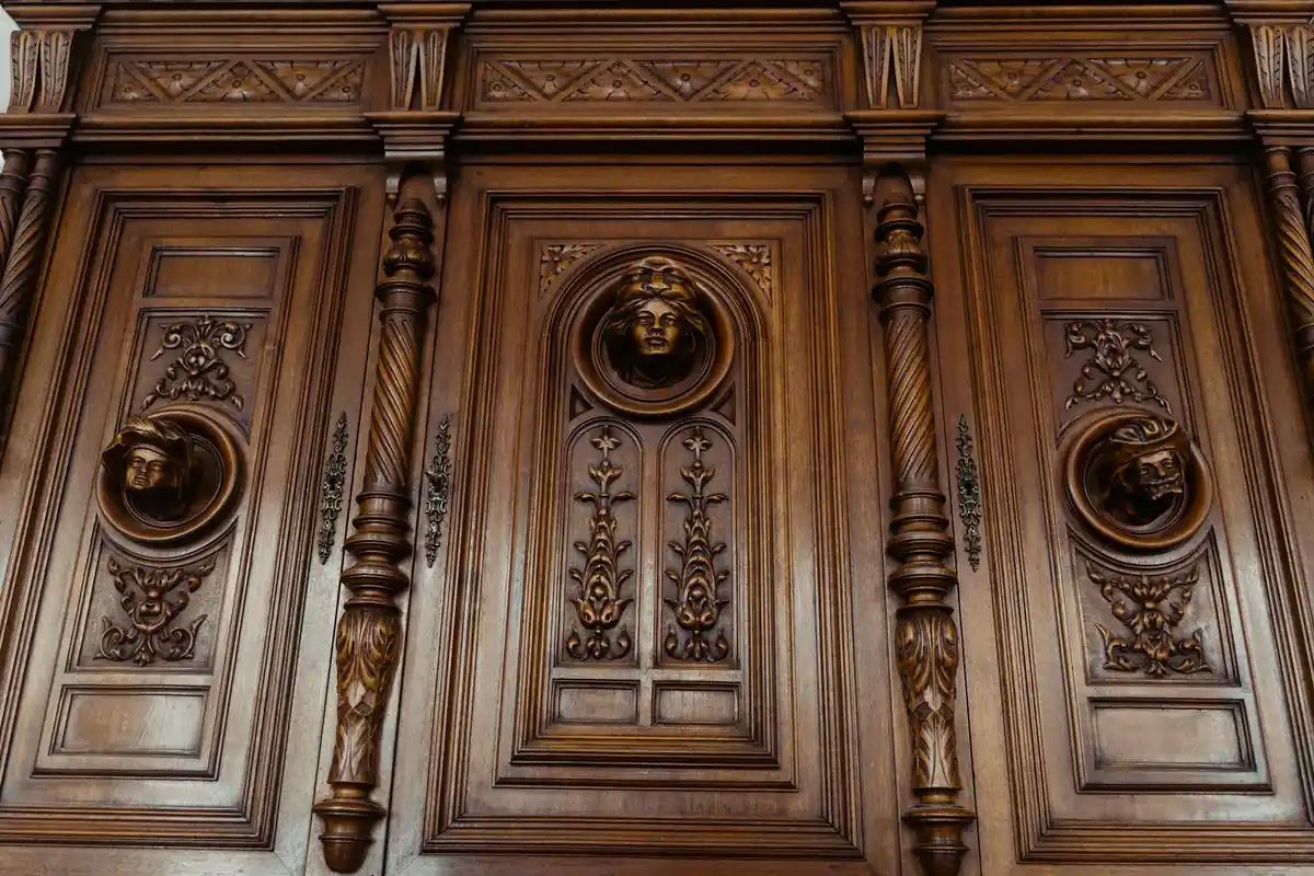Close-up of richly carved, dark hardwood panels with circular medallions and turned columns—typical of traditional mahogany doors.