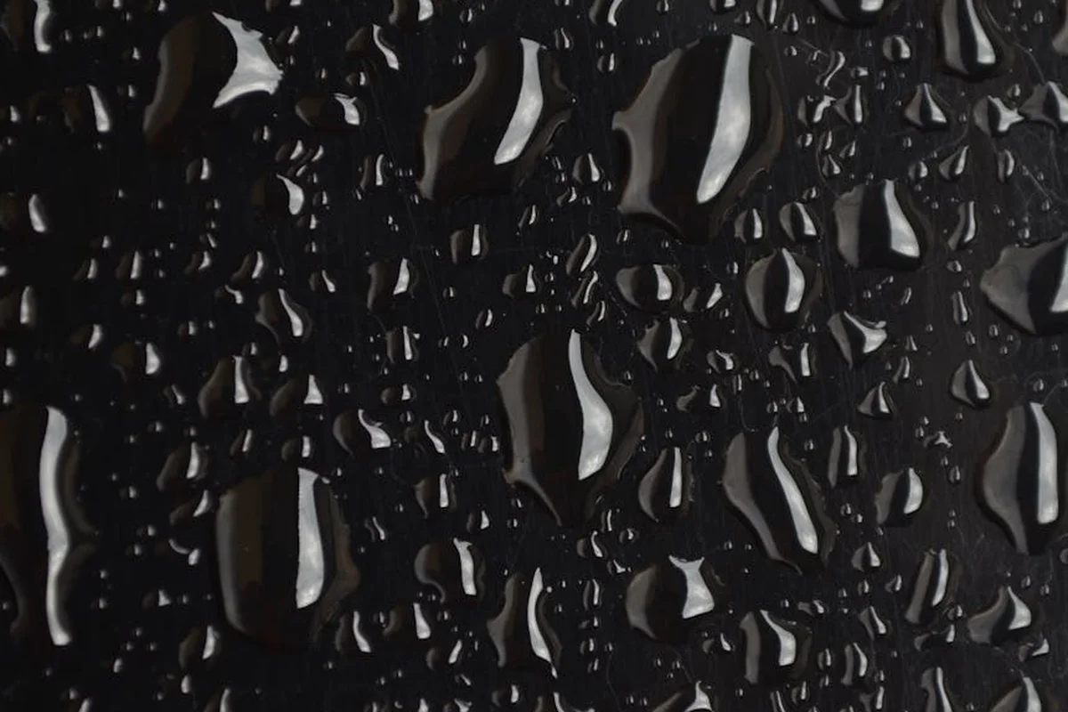 Close-up of water droplets on a dark surface, symbolizing moisture in a woodworking workshop.