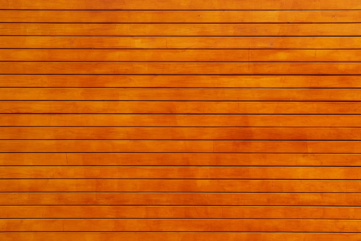 Close-up of orange-stained wooden planks with visible grain lines, illustrating wood porosity.