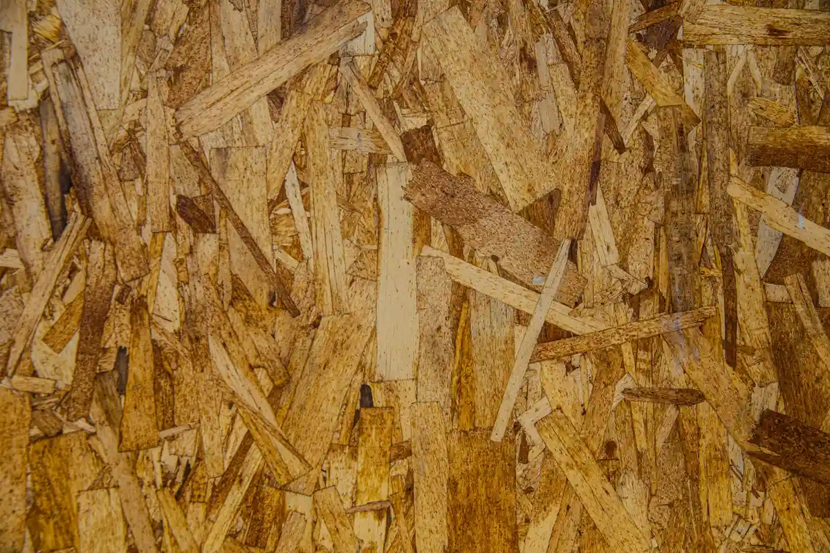 Close-up of an oriented strand board (OSB) panel surface, showing randomly arranged wood strands.