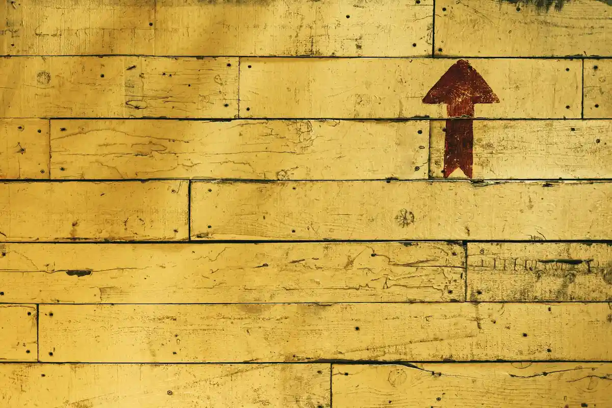 Yellow wooden boards with a red upward-pointing arrow