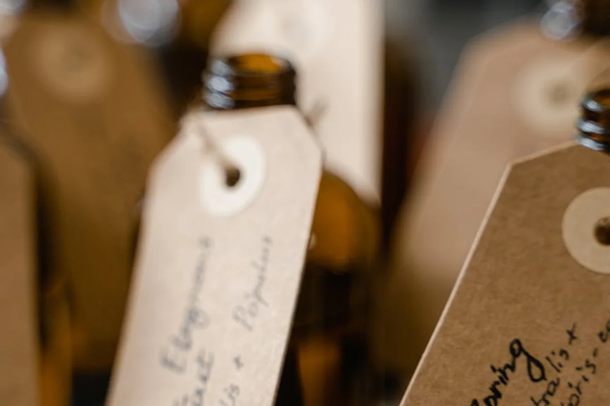 Close-up of amber oil bottles with handwritten tags in a workshop