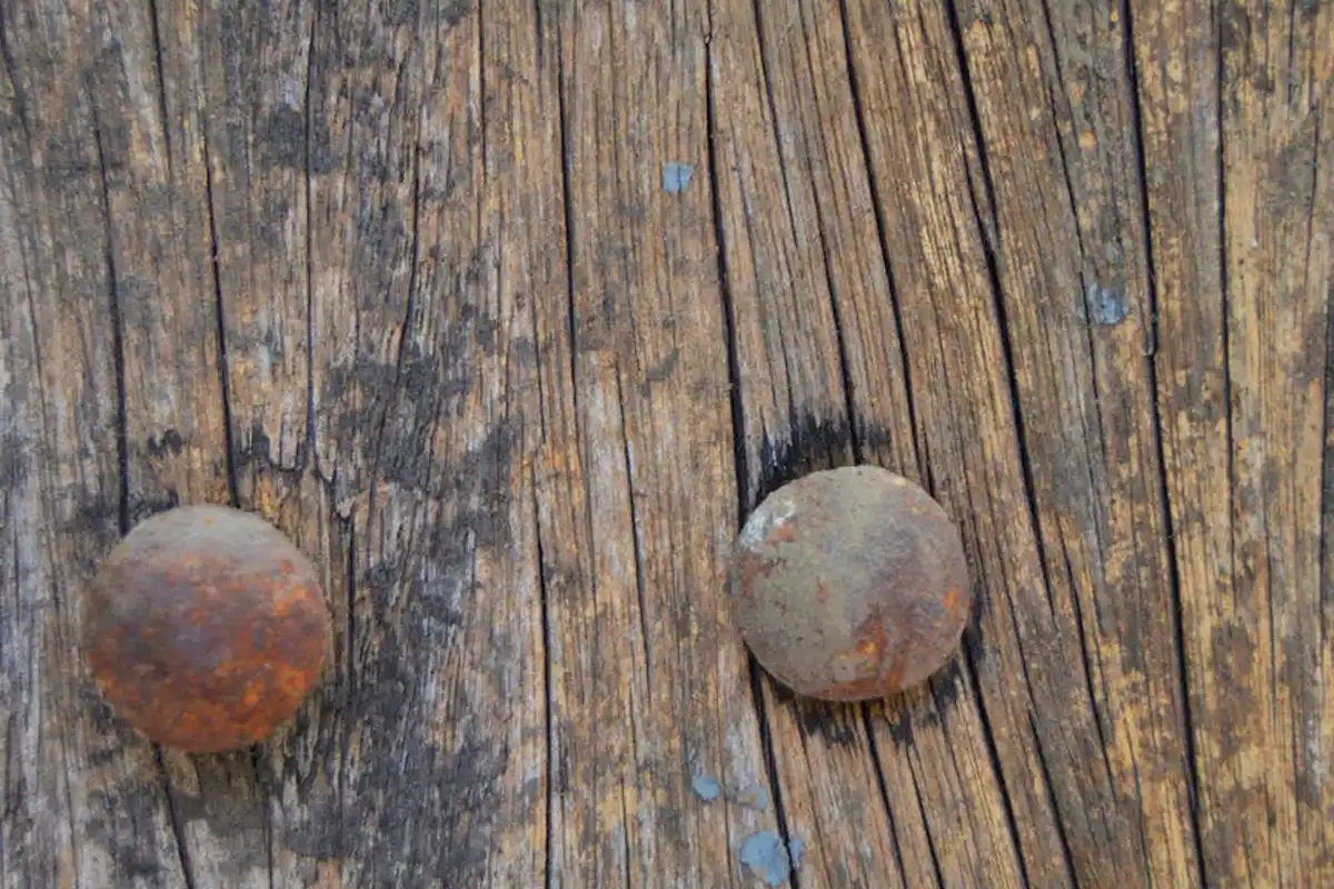Two rusty circular metal objects on weathered wood, illustrating rust stains that affect wood finishes