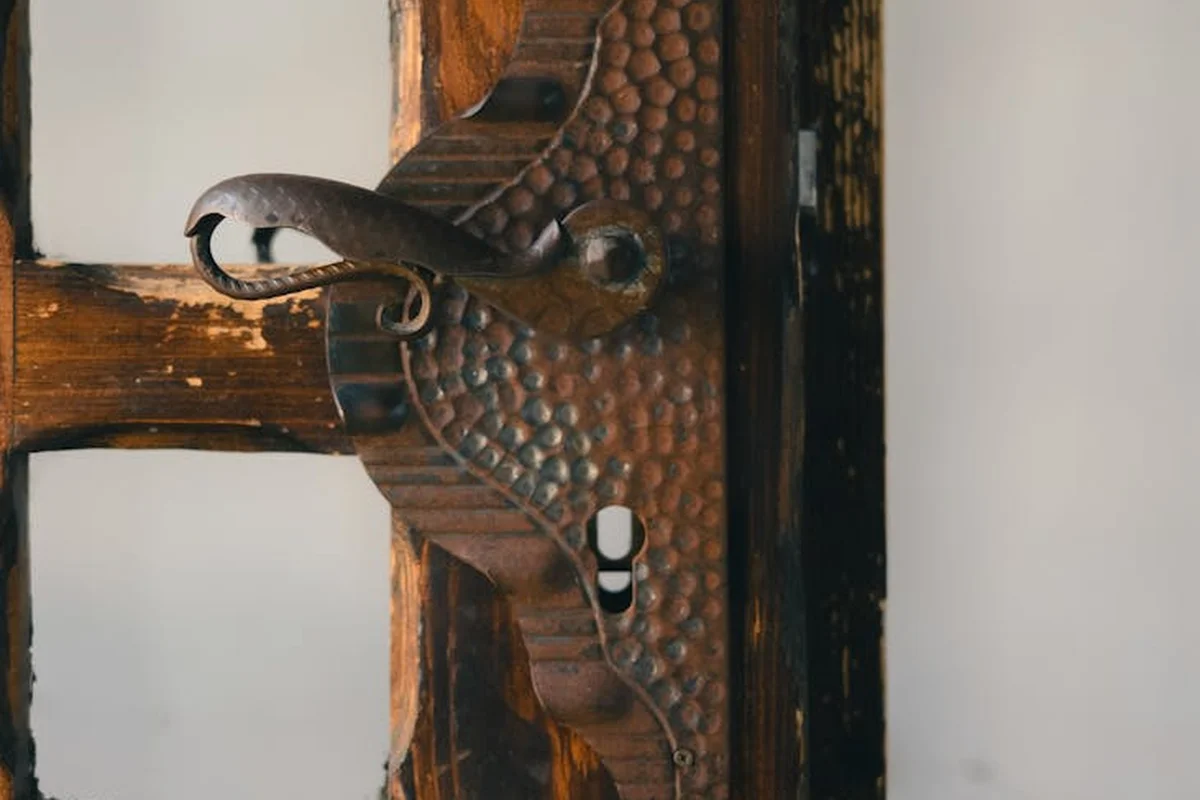 Close-up of a rustic wooden frame with hammered metal hinge and latch.