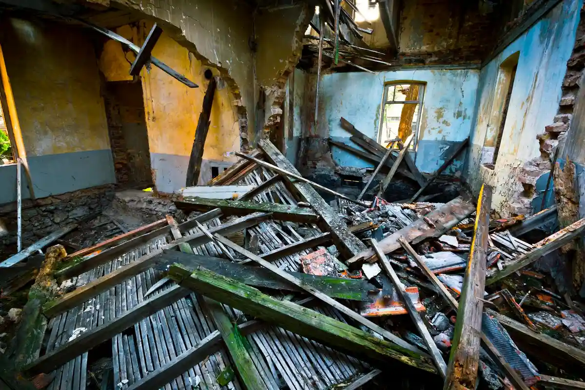 Interior of a dilapidated room with broken timber, peeling paint, and scattered debris, representing a challenging environment for epoxy consolidation.