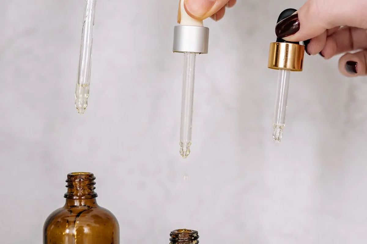 Close-up of glass droppers dispensing Danish oil above brown glass bottles, illustrating careful, controlled application for wood protection.