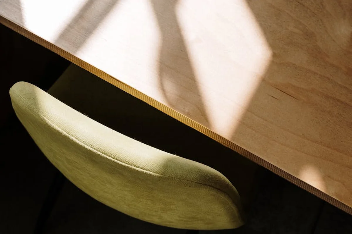Overhead view of a pale-green upholstered chair tucked under a wooden worktable.
