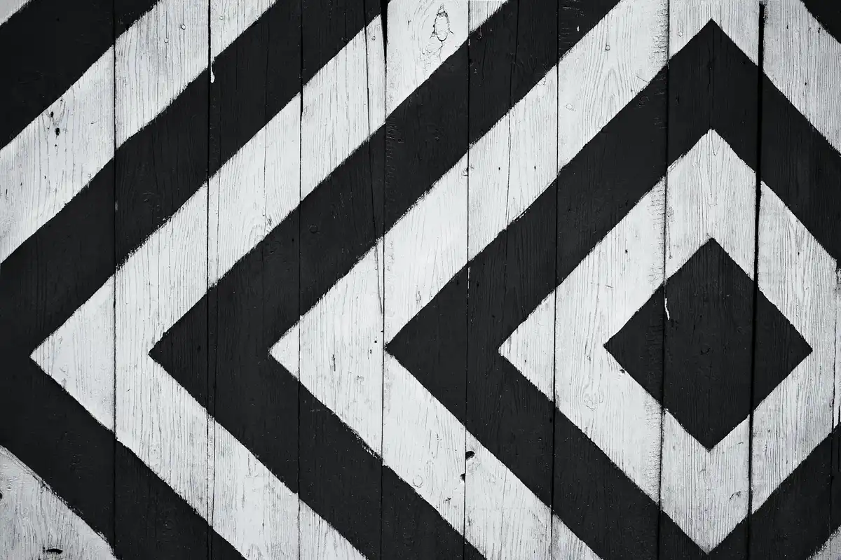 Patterned wooden planks with bold black geometric shapes painted on light-colored wood.