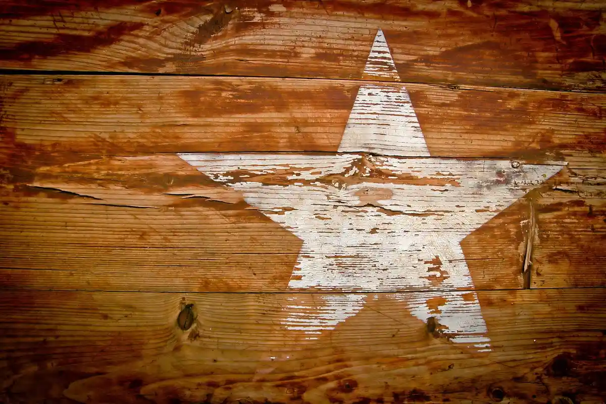 Teak wood deck planks with a white star painted on the surface, showing weathered grain.