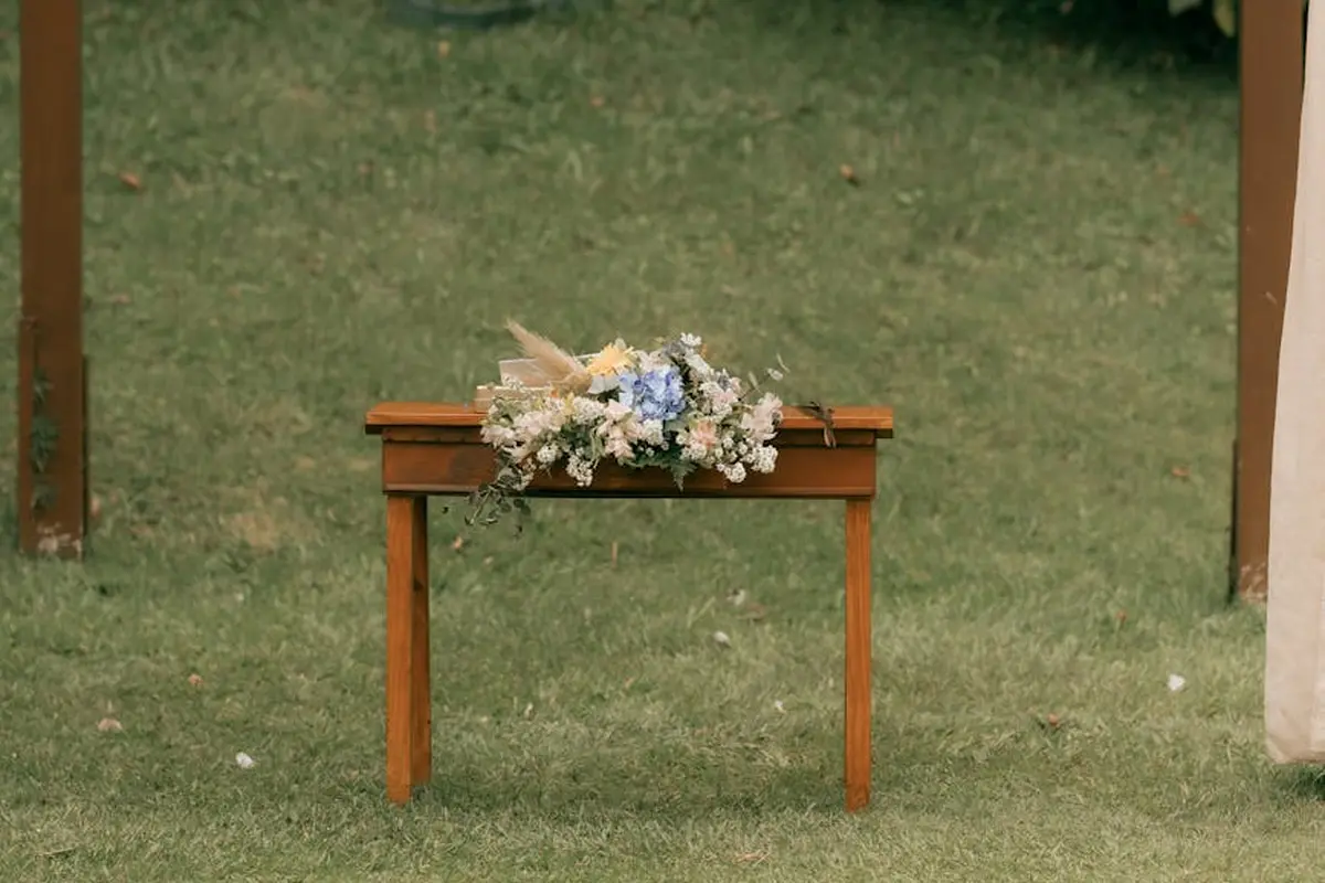 Small teak table with a floral arrangement on a grassy lawn