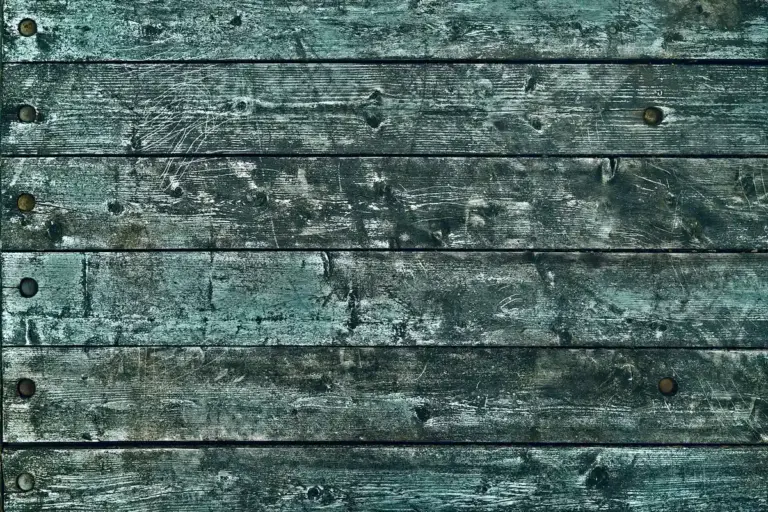 Weathered teal-painted wooden planks with visible scratches and wear.