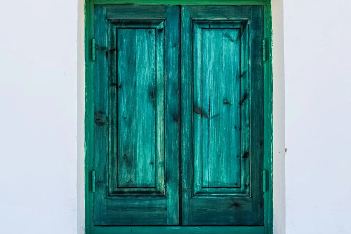 Teal-green double wooden doors with panel details and dark hardware