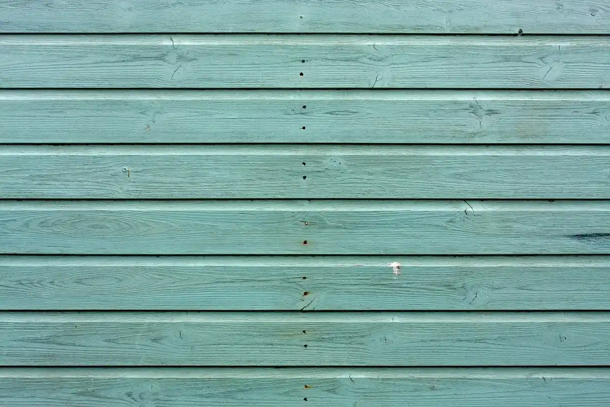 Blue-green horizontal wooden planks with weathered texture (siding).
