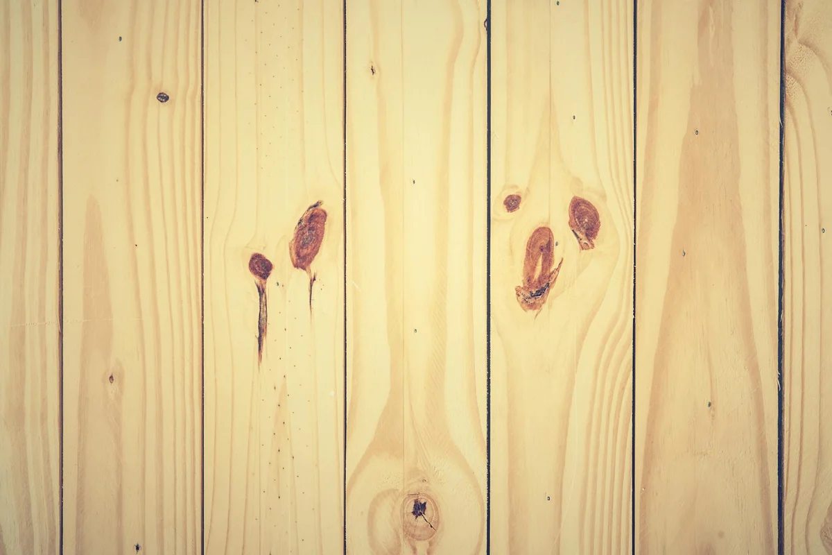 Close-up of vertical pine boards showing grain and knots, typical of pine lumber used for lightening and staining tests.