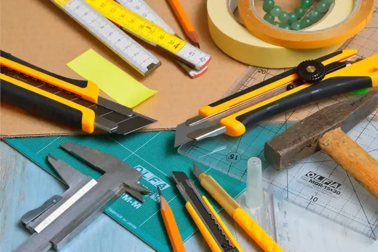 Assorted woodworking tools on a workbench, including rulers, tape measures, knives, and pliers, ready for precision projects.