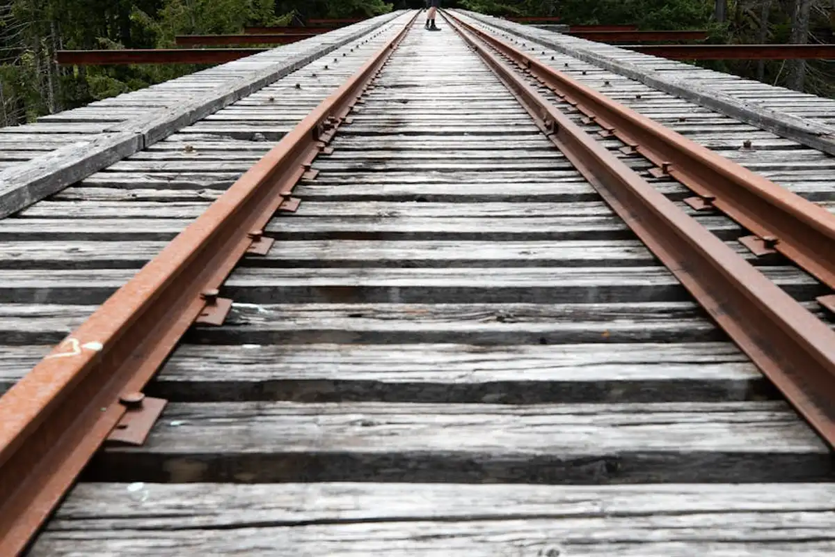 Close-up perspective of weathered wooden railroad ties with metal rails receding into the distance.