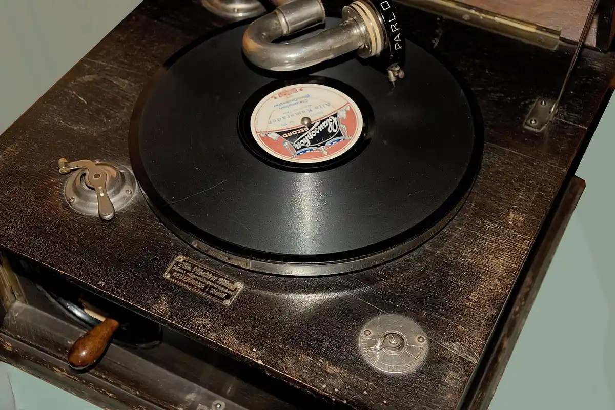 Vintage wooden turntable with a black vinyl record on a wooden surface.