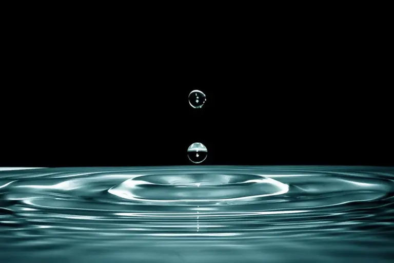 Close-up of a water droplet hitting a surface and forming concentric ripples, symbolizing ultrasonic cleaning action.