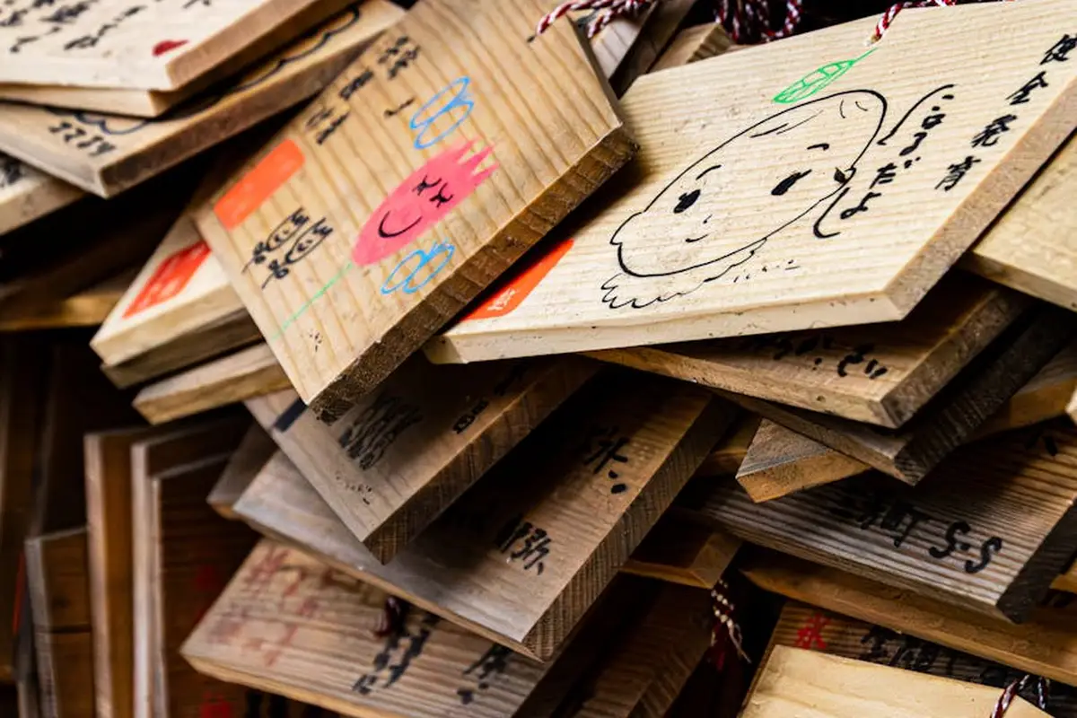 Pile of wooden boards with handwritten markings and doodles, representing sample pieces for finishing tests.