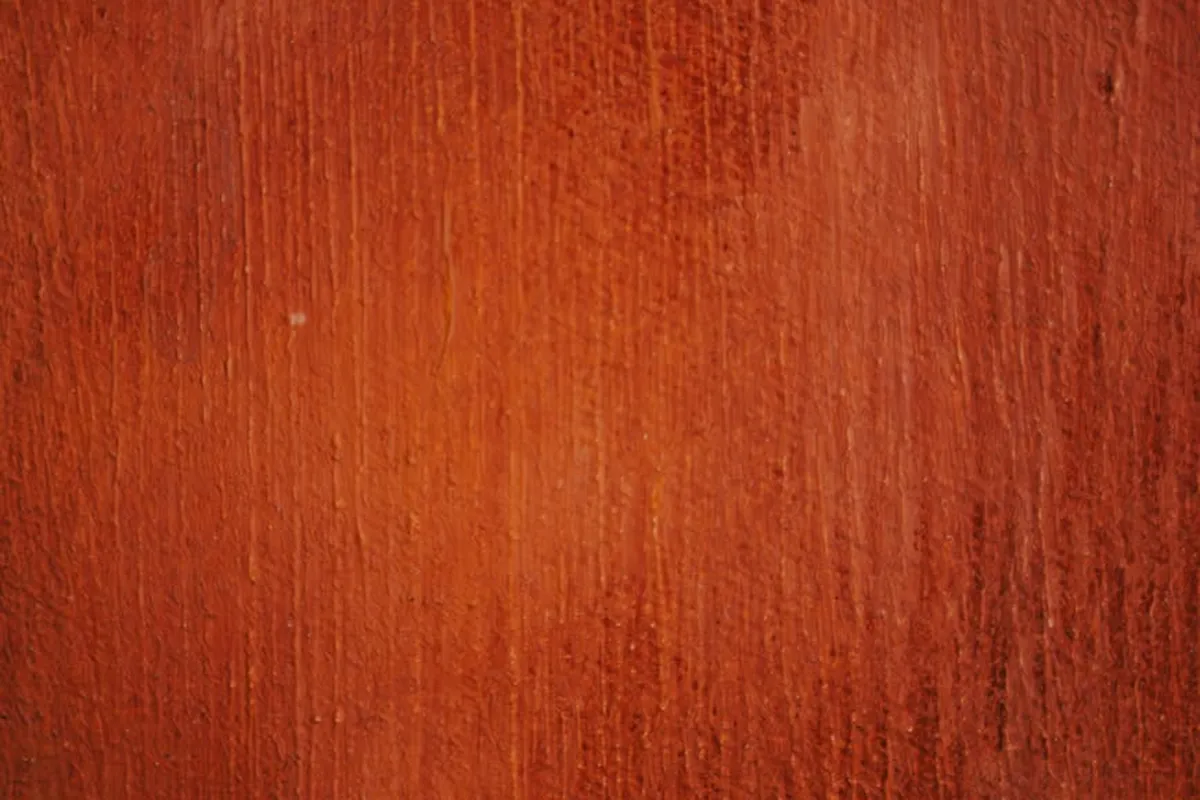 Close-up of walnut wood with rich reddish-brown grain and subtle vertical lines