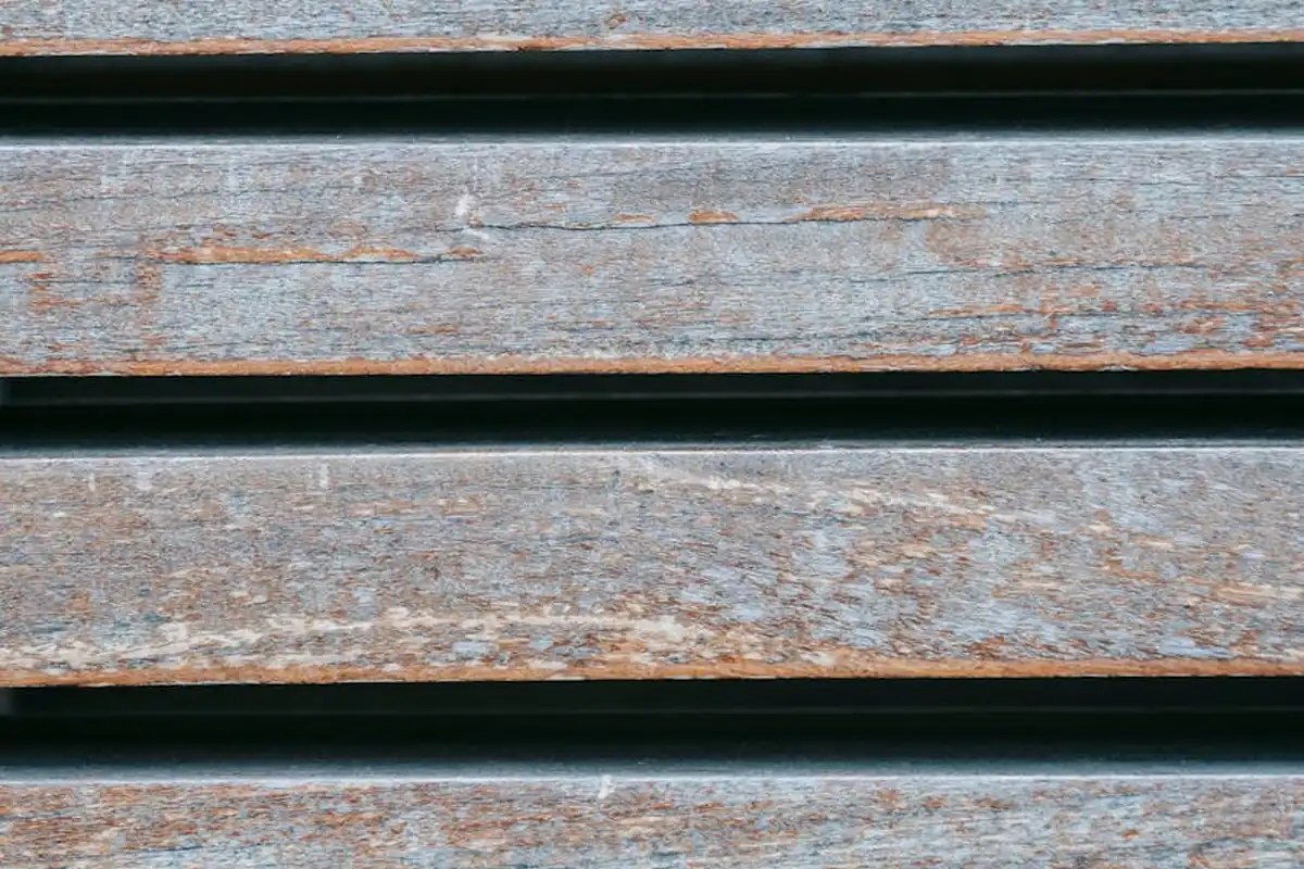 Close-up of weathered wooden slats with visible gaps, illustrating moisture-induced swelling and dimensional changes in wood-based panels.