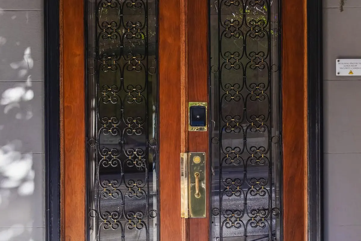 Exterior wooden door with decorative wrought-iron grille, demonstrating a wood surface exposed to outdoor UV light.