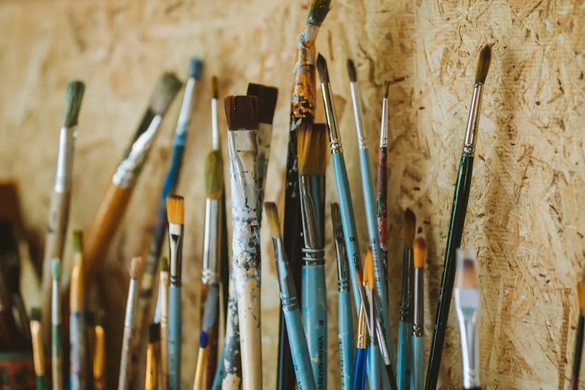Assorted wood finishing brushes with stained bristles arranged in a workshop, ready for cleaning