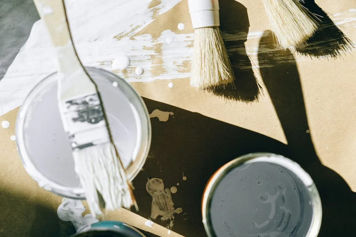 Brushes and containers with solvent on a wooden workbench, illustrating storage and upkeep for wood finishing tools