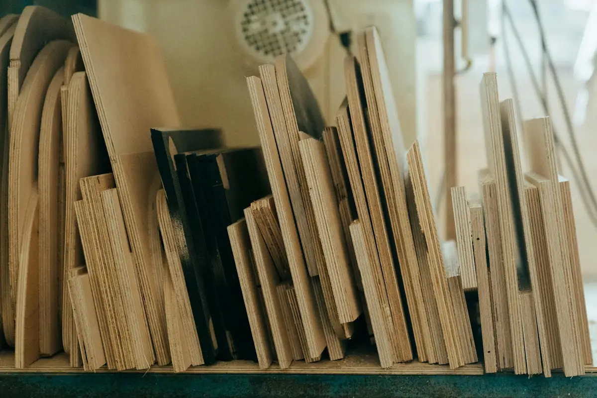 A row of wooden boards and plywood strips standing upright on a workbench, displaying varied grain patterns and colors for grain-reading reference.