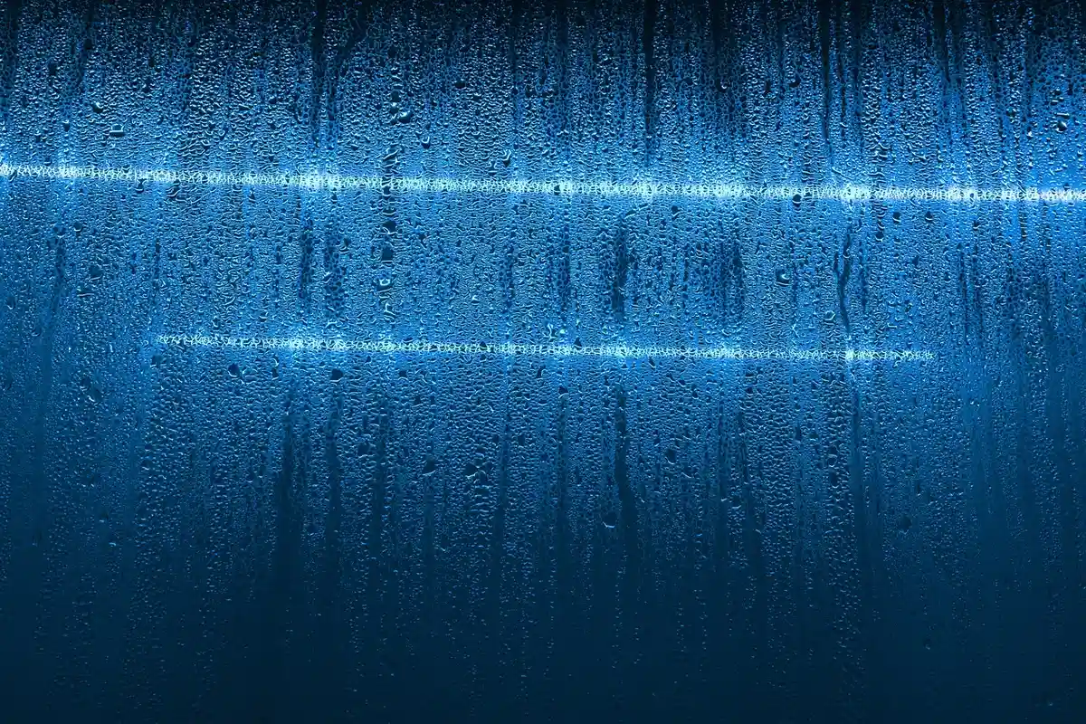 Blue lab surface with water droplets and light reflections, suggesting a controlled testing environment
