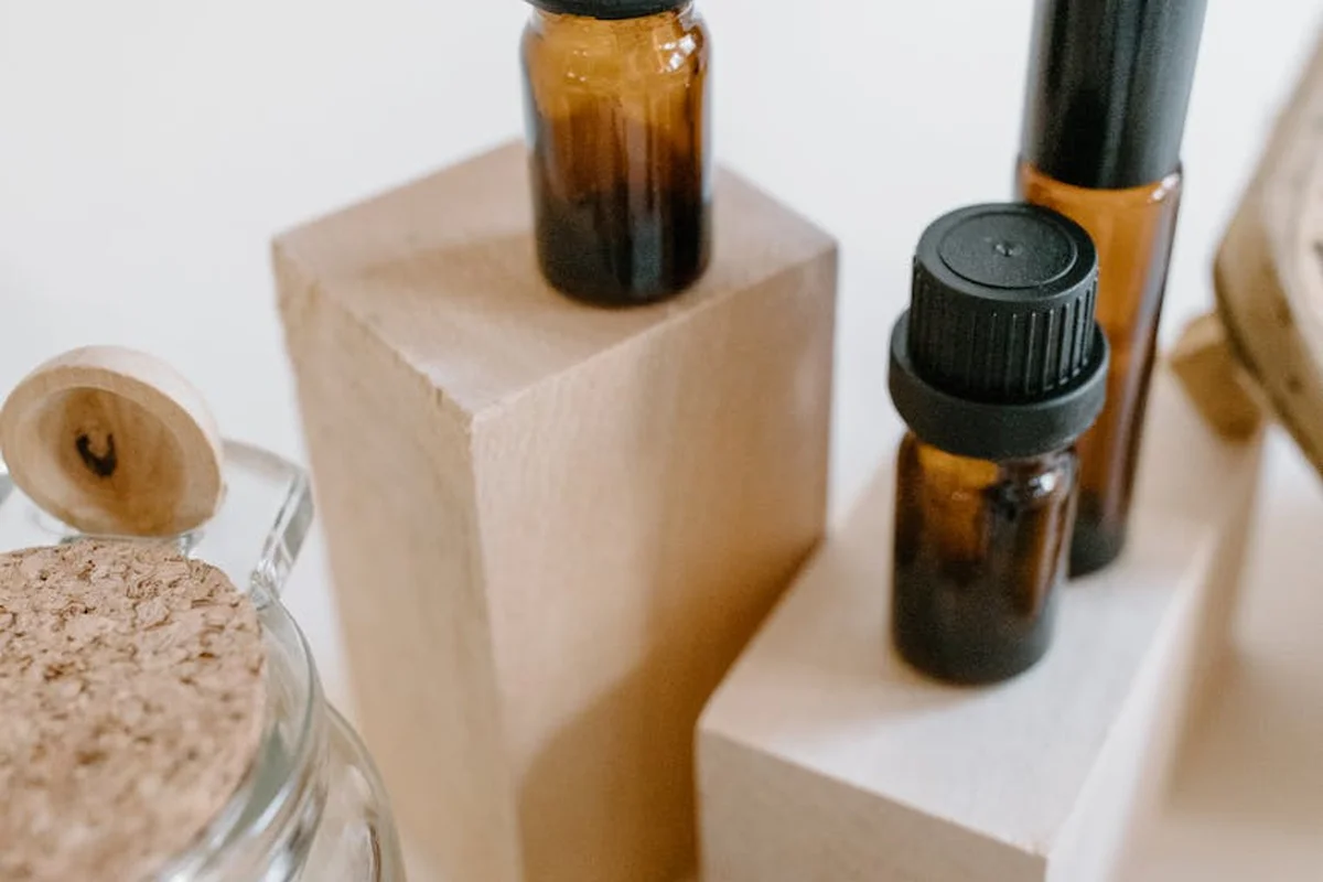 Assorted amber glass bottles containing wood finishing oils arranged on light wooden blocks for a finishing demonstration.